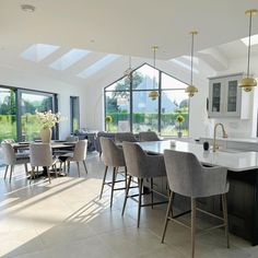 a large kitchen and dining room with an island in the middle, surrounded by windows