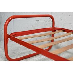 a red metal bed frame with wooden slats