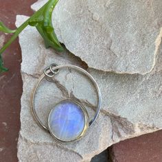 "Rainbow moonstone has always been one of my favorites, with its blue and purple flashes, and this stone is no exception, it's got a GORGEOUS flash. Moonstone is said to represent feminine power and hope, but is most commonly known to be the birthstone for those lucky enough to be born in June. A rainbow moonstone is set in a sterling and fine silver bezel. I cut the back of the bezel out because when the light hits it just right, she just glows. The stone sits on top of a circular base which has two jump rings that I left open so you can string it onto a necklace of your choosing. This one-of-a-kind pendant is approximately 1.5\" in diameter. Please note that this listing is for the pendant only; necklace is not included. This pendant is definitely a statement pendant, so I recommend pair Bohemian Moonstone Cabochon Jewelry, Unique Moonstone Healing Jewelry, Unique Moonstone Jewelry For Healing, Mystical Moonstone Jewelry With Large Stone, Moonstone Jewelry With Large Round Stone, Round Moonstone Jewelry With Large Stone, Unique Large Moonstone Ring, Unique Moonstone Ring With Large Stone, Moonstone Round Pendant For Healing