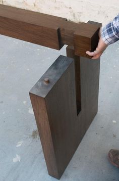 a person standing next to a piece of wood that has been made into a bench