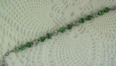 "Shades of green are displayed in this sparkling Swarovski cup chain bracelet. Each carefully hand set 8mm (39ss) crystal is held with four prongs in an antique silver ox 15 cup bracelet, closed with a lobster claw clasp. The peridot, erinite and chrysolite crystals blend in lovely shades of green bracelet. These chatons are set in this nickle free metal, silver toned bracelet. A 2 1/2\" extender chain finished with an peridot Swarovski bead making this bracelet adjust from 6 1/2\" to 8 3/4\", f Green Crystal Bracelet With Rhinestones, Green Crystal Bracelet For Weddings, Green Crystal Wedding Bracelet, Green Crystal Round Bracelets, Green Crystal Bracelets With Sparkling Stones, Green Rhinestone Bracelets For Wedding, Cup Chain Bracelet, Violet Necklace, Bracelet Emerald