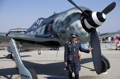 a man in uniform standing next to an airplane