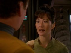 a woman talking to a man in front of a television screen with the words star trek on it