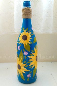 a blue bottle with sunflowers painted on it and rope wrapped around the top