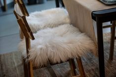 a table with two chairs and a white sheepskin chair cover on it's back