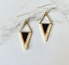 the beaded triangle earrings in black and white are hanging from gold earwires