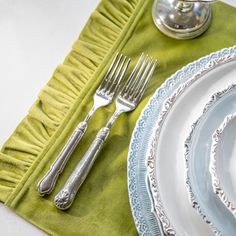 a table set with silverware and green napkins