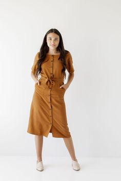 Introducing the 'Bronwyn' Tencel dress! This flattering dress features a button front detail and is finished off with a beautiful belt that ties together an entire look. Pair with low heels for an elevated and sophisticated office look! Exclusively designed by us with you in mind. 75% Tencel 25% Linen Hand Wash Cold Do Not Bleach Hang to Dry Low Iron if Needed Do Not Dry Clean Unlined Functional, nursing friendly buttons! Model Height 5'7" | Wearing Size Small Please carefully measure a similar Formal Button-up Midi Dress With Tie Waist, Fitted Brown Dress With Belt, Belted Midi Dress For Office Wear, Casual Belted Midi Dress For Office Wear, Mid-length Midi Dress With Button Closure For Work, Midi Workwear Dress With Button Closure, Midi Dress With Button Closure For Work, Workwear Midi Dress With Button Closure, Belted Mid-length Fall Dress