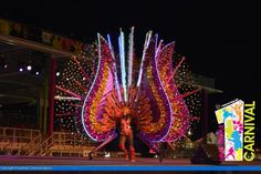 a woman is standing in front of a carnival display at night with lights on her body