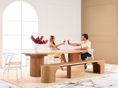 a man and woman sitting at a table with wine glasses in their hands, one holding the other's hand