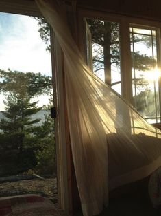 the sun is shining through the sheered curtains in this bedroom with an ocean view