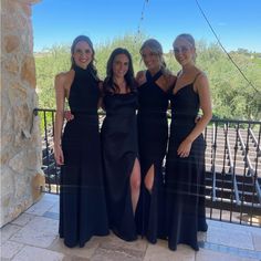 three women in black dresses standing next to each other on a balcony with stone steps