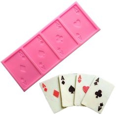 four playing cards are next to a pink mold