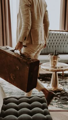 a man carrying a suit case across a living room with a coffee table and couch