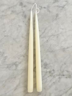 two white candles sitting on top of a marble counter