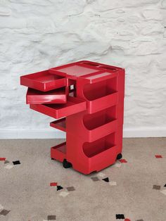 a red desk with three drawers on it and a white wall in the back ground