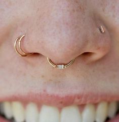 a woman's nose with two gold hooped nose rings on top of it