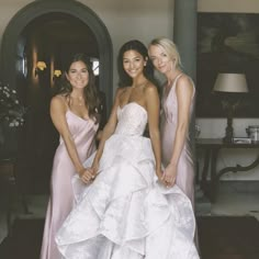 three beautiful women standing next to each other in front of a doorway wearing pink dresses