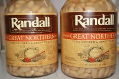 two jars filled with white beans sitting on top of a counter next to each other