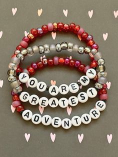 Some people are just incredible. You are my greatest adventure set of three handmade beaded stretch bracelets.  Varying shades of red and grey glass pony beads make this the perfect display of love.  Bracelets are available in a variety of lengths.  Pick your custom length from the drop down menu below.  All our bracelets are made with quality in mind.  With that being said, all bracelets should be treated with care while putting on, wearing, and taking off.  Keep dry. Do not swim or bath with t Snowflake Bracelet, Make Your Own Bracelet, Letter Bracelet, Jewelry Beaded, Couple Gift, Star Bracelet, Grey Glass, Layered Jewelry, Greatest Adventure