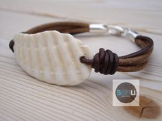 a white shell on a brown leather bracelet