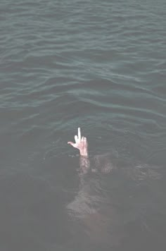 a person floating in the water with their hand up