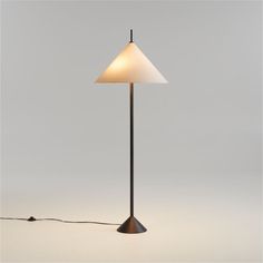 a floor lamp with a white shade on it's side and a cord attached to the base