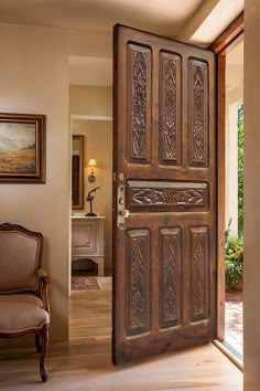 an ornate wooden door is open to the living room