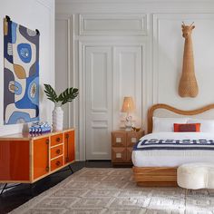 a bedroom with white walls and an orange dresser