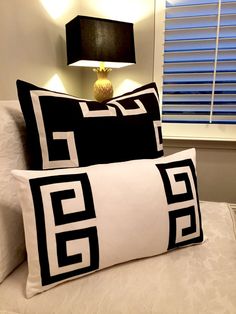 two black and white pillows sitting on top of a bed next to a night stand