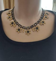 a black and gold necklace on a mannequin neckline with flowers in the center