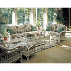 a living room filled with lots of furniture next to a large glass window covered in plants