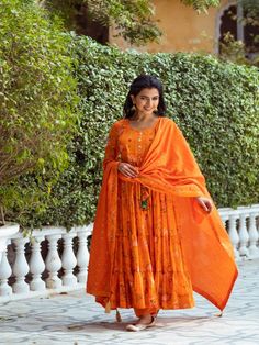 This Set Has a Anarkali, bottom and dupatta. Floral printed tier Anarkali set with hand embroided yoke. It is paired with matching chanderi foil print dupatta enhanced with fabric detailing and palazzo pants. Color: Orange Fabric: Anarkali - Cotton Silk Bottom - Shantoon Dupatta - Chanderi Product Details: Neck Type - Round neck Anarkali Length - 50 inches Bottom Length - 38-40 inches Sleeve Length - 22 inches Note: Available in other colors The product will be delivered within 2-4 weeks of orde Orange Anarkali Palazzo Set With Gota Work, Orange Anarkali Palazzo Set With Traditional Drape, Unstitched Maxi Length Traditional Wear With Gota Work, Orange Chanderi Anarkali Set For Navratri, Festive Orange Palazzo Set With Chikankari Embroidery, Orange Chanderi Anarkali Set With Cutdana, Designer Cotton Silk Salwar Kameez Maxi Length, Unstitched Maxi Length Anarkali Set With Gota Work, Maxi Length Chanderi Salwar Kameez With Gota Work