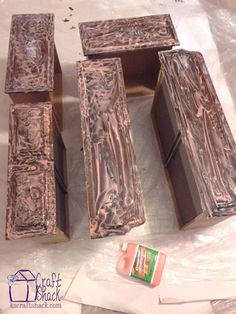 three wooden boxes sitting on top of a table covered in plastic wrap and some other items