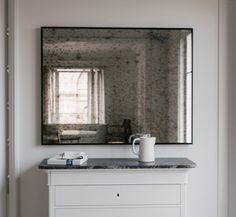 a white dresser with a mirror above it