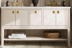 a bathroom vanity with two sinks and gold faucets on the top, next to a towel rack