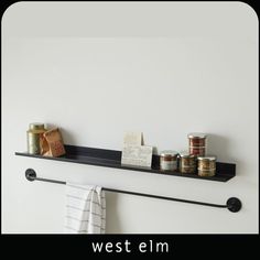 a black shelf with spices and jars on it next to a towel rack that says west elm