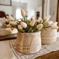 white tulips are in a wooden vase on a doily with a mirror in the background