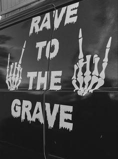 black and white photograph of the side of a van with graffiti on it that says rave to the grave