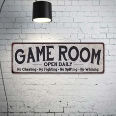 a sign that says game room open daily hanging on the wall next to a lamp