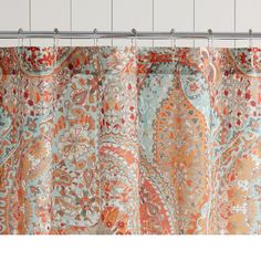 a shower curtain with an orange and blue paisley pattern on the outside, hanging from a metal rod