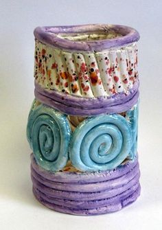 three different colored ceramic vases stacked on top of each other, one with spiral designs