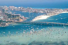 an aerial view of the ocean with boats in the water and a bridge crossing over it