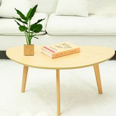 a white couch sitting next to a table with a book on it and a potted plant