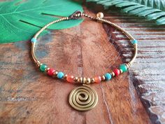 This is our crystal gemstine spiral queen anklet, which features a golden brass spiral at the centre, bordered by orange agate, turquoise, red howlite and jade gemstones. The crystal anklet is embellished with golden brass beads and curved brass tube bars! Perfect to embody your bohochic style, from beachwear to daywear all year round! The anklet is held together with dark brown macramé waxed cord and fastens with a strong bell and loop at two lengths: 24cm 26cm Please do measure your ankle to e Handmade Jewelry For Summer Meditation, Bohemian Nickel-free Anklets For Festivals, Adjustable Nickel-free Bohemian Anklets, Bohemian Gold Beaded Bracelets For Meditation, Adjustable Bohemian Brass Beaded Bracelets, Festival Brass Jewelry With Tiny Beads, Gold Beaded Bracelets With Natural Stones For Festivals, Bohemian Adjustable Anklets With Round Beads, Bohemian Gold Beaded Nickel-free Bracelets