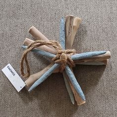 a piece of driftwood is tied up with twine on the floor next to a tag