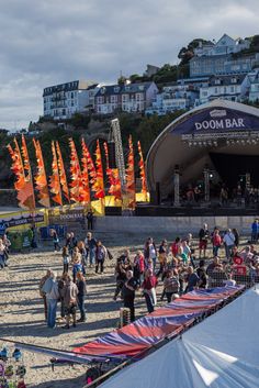 a group of people standing on top of a sandy beach next to an open air stage