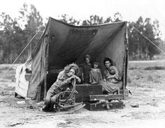 an old black and white photo of some people in a tent with suitcases on the ground