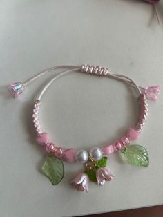 a bracelet with flowers, leaves and pearls is shown on a table next to a pair of scissors