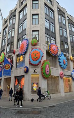 people are walking in front of a building with colorful decorations on the side of it